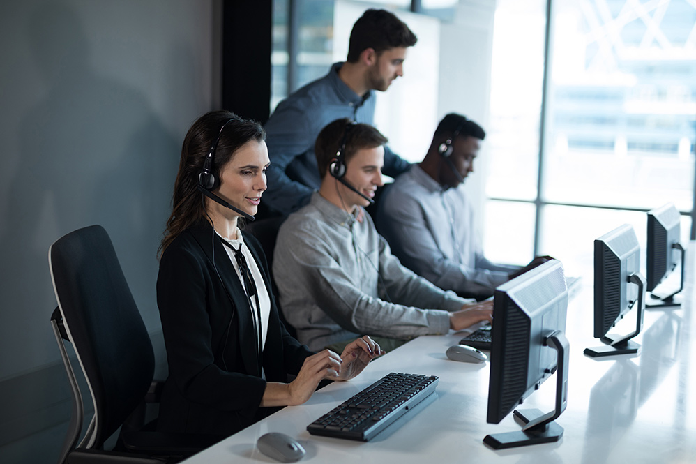 A group of people wearing headsets are working in an office.