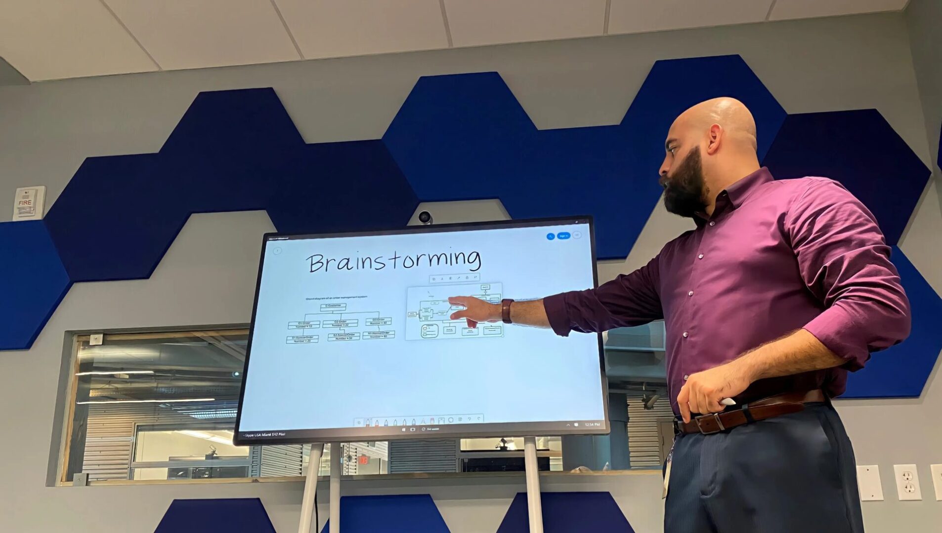 Man in purple shirt brainstorming on large screen.