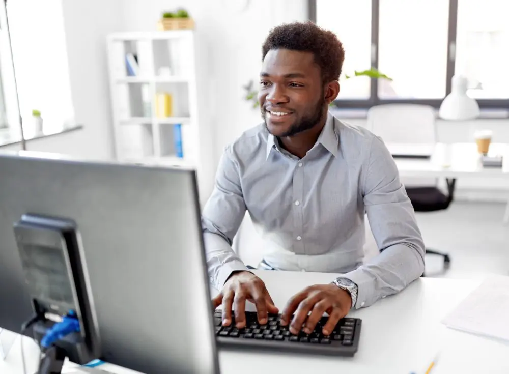 A smiling businessman types on a computer keyboard.