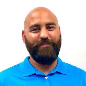 Headshot of a bald man with a beard wearing a blue shirt.